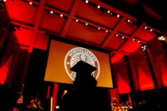 Silhouette of a person at the Seattle Commencement ceremony in 2023 wearing a cap and gown.