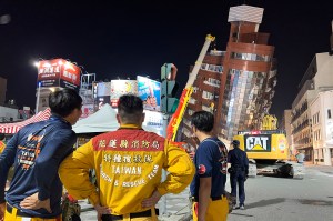 Rescue workers standing near the site of a leaning building in Taiwan.