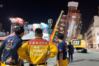 Rescue workers standing near the site of a leaning building in Taiwan.