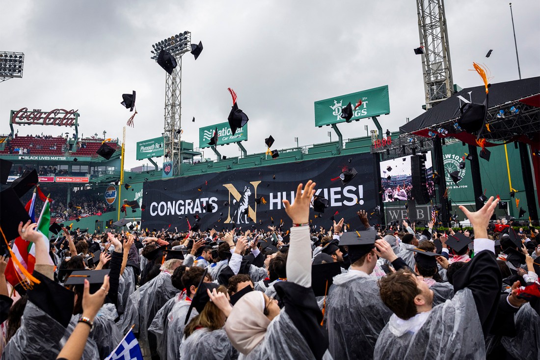 Graduates wearing ponchos tossing their caps in the air.