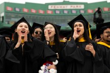 Three graduates cheering at the Commencement ceremony at Fenway Park.