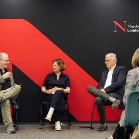 A panel of people sitting in front of a Northeastern branded backdrop.