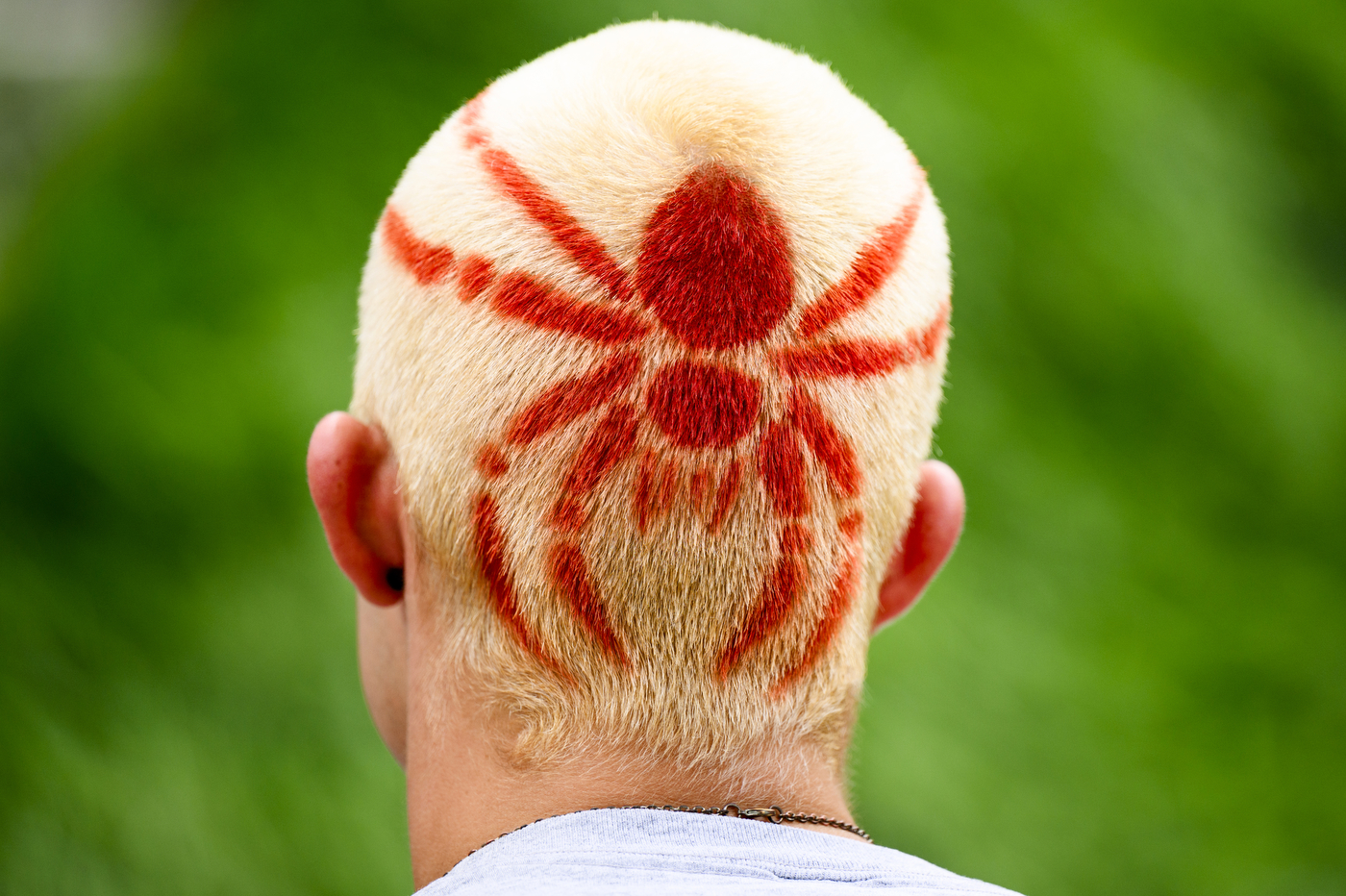 An orange spider design dyed onto the back of someone's blonde hair.