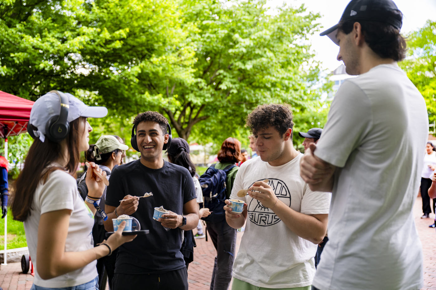 Four people stand in a circle, laughing while enjoying ice cream.