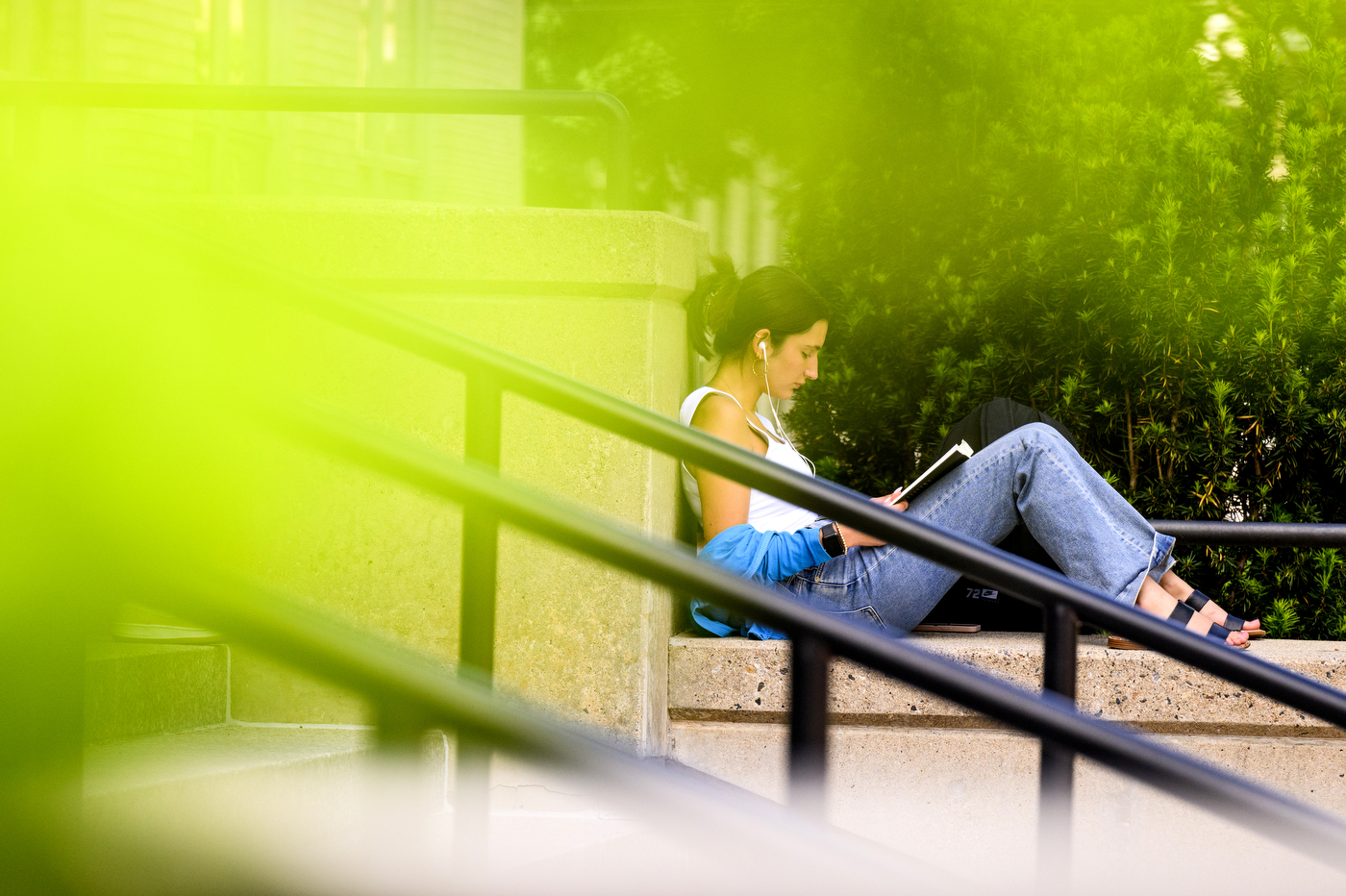 A person reads outside on a set of steps.