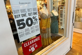 A sign in a clothing stoor saying 'Buy one get one 50% off'.