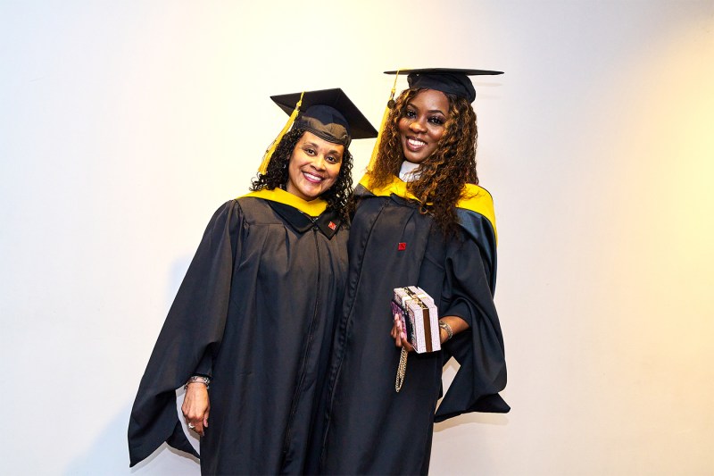 Two students posing in their caps and gowns.