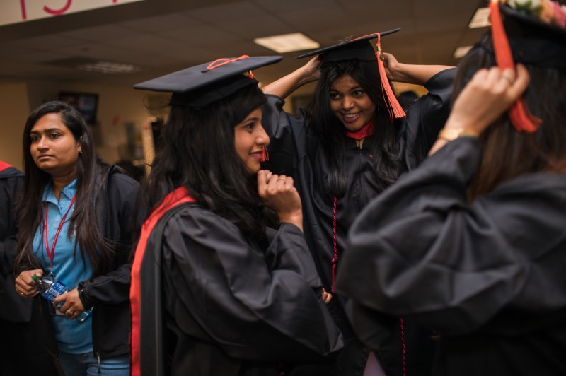 People adjust their regalia at Seattle's Commencement ceremony.