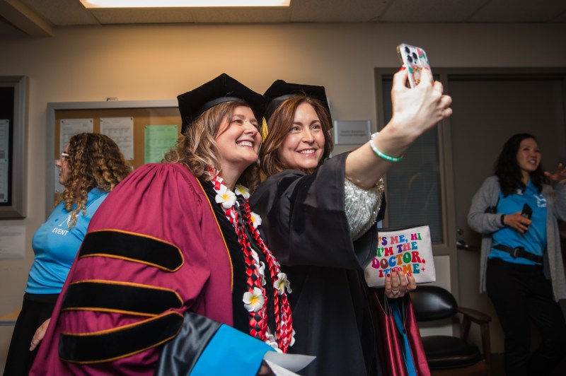 Two people take a picture at Seattle's Commencement ceremony. 