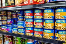 Tins of Planters peanuts on a grocery store shelf.