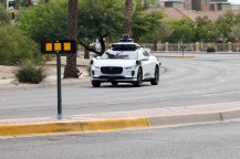 A white driverless car driving down a street in Arizona.