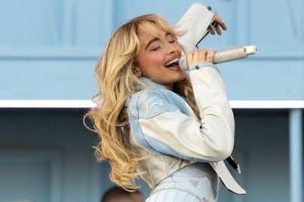 Sabrina Carpenter performs onstage while wearing a denim jacket and skirt.