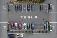Tesla cars sitting in a parking lot branded with the Tesla logo.