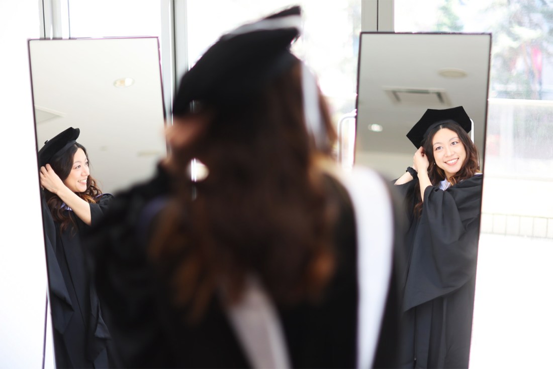 A graduate fixing their cap in the mirror at the 2024 Vancouver Convocation.