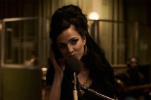 Screen capture of the actress playing Amy Winehouse in the 'Back to Black' biopic singing into a microphone.