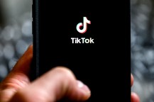 A person holding their phone up to a black screen showing the TikTok logo.