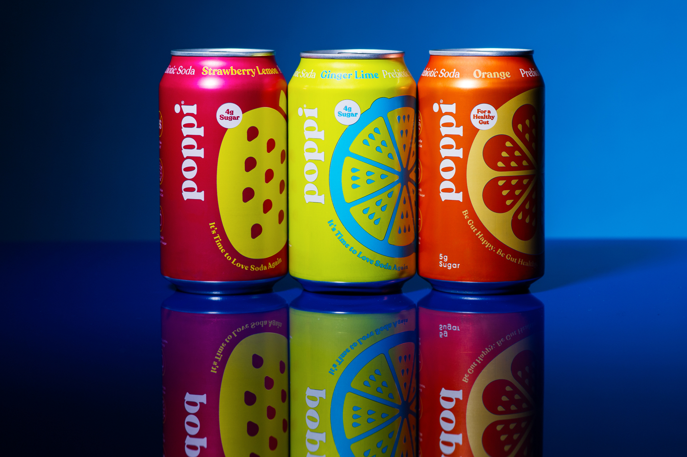 Three cans of Poppi soda on a blue background.