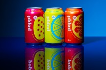 Three cans of Poppi soda on a blue background.