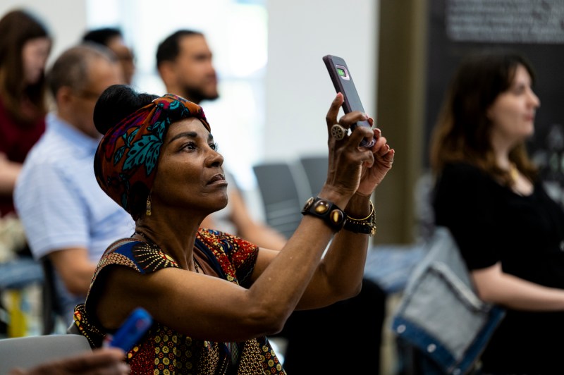 An audience member taking a photo on their phone at Northeastern's 2024 Juneteenth Celebration.