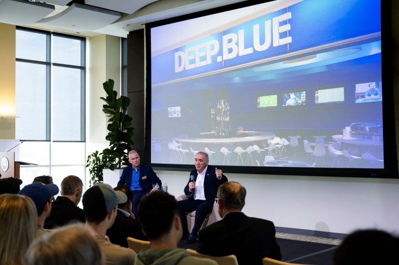 David D. Cramer dan Garry Kasparov duduk bersebelahan di depan layar yang memperlihatkan bagian dalam Deep Blue, sistem catur ahli.