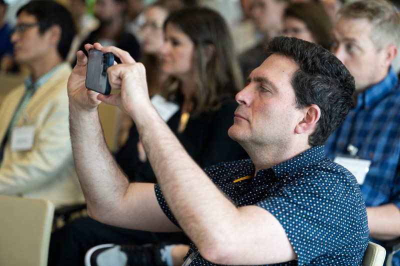 An audience member taking a photo of the fireside chat on their iPhone.