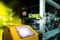 Oscar De La Garza works on a yellow Amazon robotic machine inside a lab.