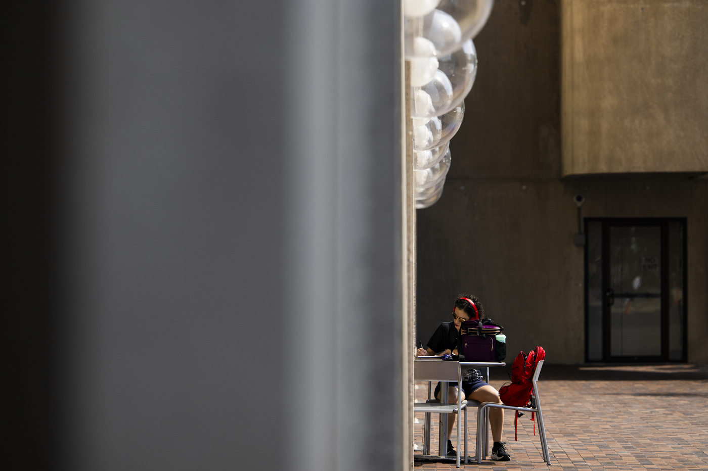 A person works on their laptop outside while sitting at a circular table.