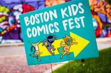A turquoise sign that says 'Boston Kids Comics Fest' with a yellow arrow and three comic cats pointing to the right.