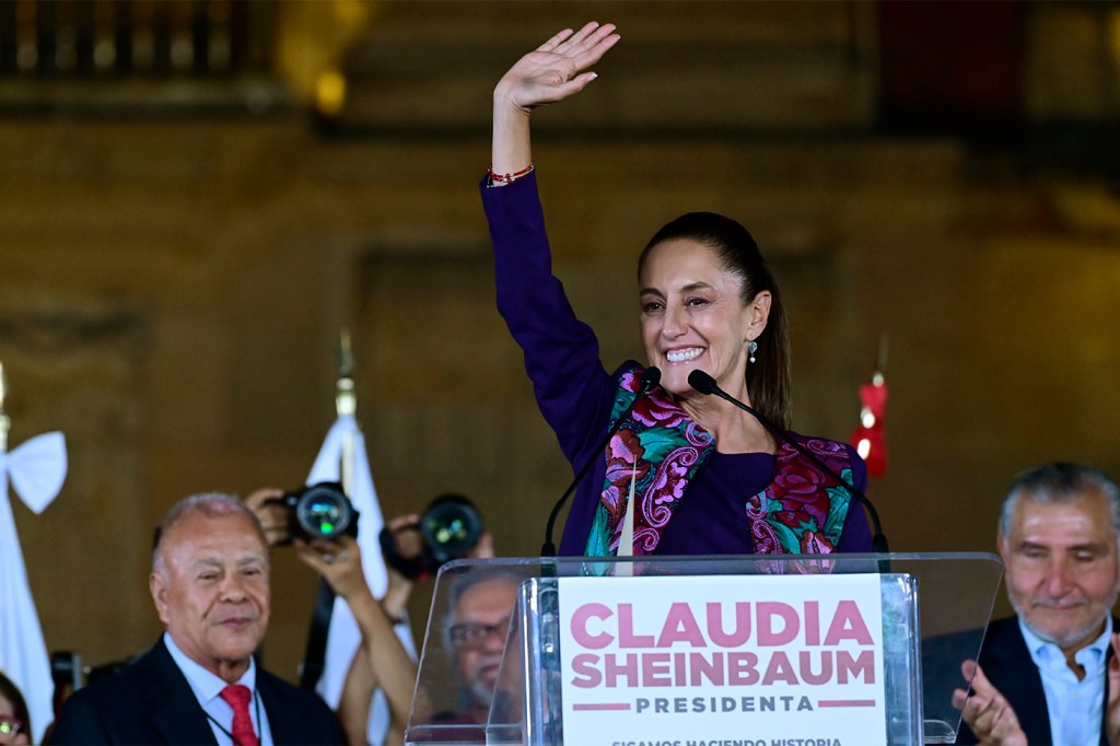 Claudia Sheinbaum standing at a podium waving.