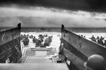 A black and white photograph of troops storming the beaches during D-Day.