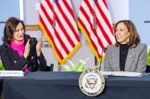 Gov. Gretchen Whitmer (left) and Vice President Kamala Harris (right) sit at a blue-colored table in front of two United States flags.