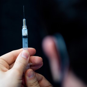 A person holding a COVID vaccine needle.