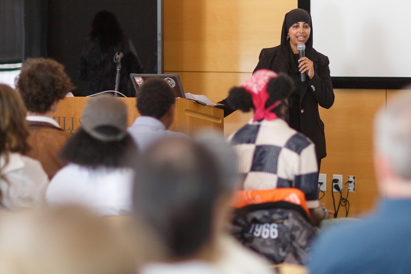 A person speaking into a microphone at the Summer Youth Employment Program ceremony.