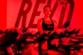 Meaghan St Marc, Owner & Trainer of Rev'd Indoor Cycling, poses for a picture in a red-colored room.