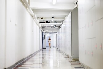 A person wearing a dress walks through a white underground hallway.