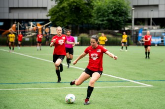 A player wearing a red jersey playing soccer in the Boston Unity Cup.