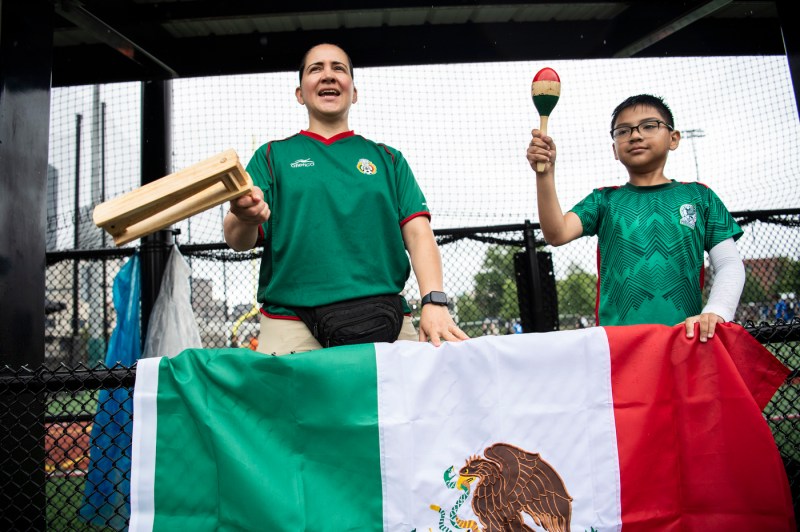 Two people shaking maracas while holding a Mexican flag at the Boston Unity Cup.