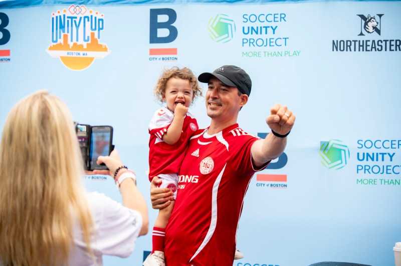 A person holding a child and their fist in the air at the Boston Unity Cup.