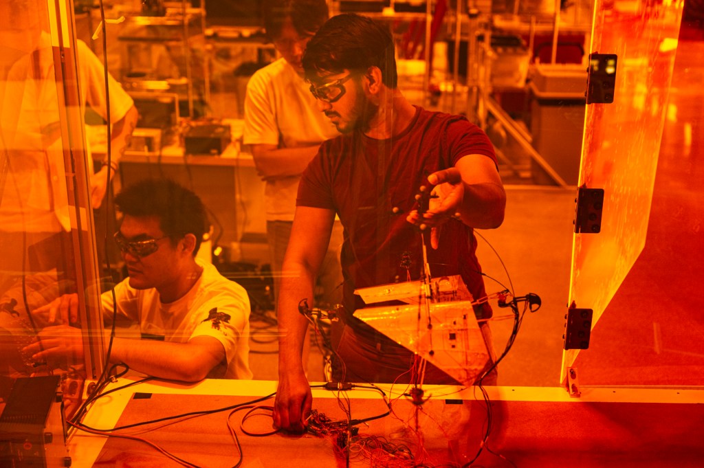 Researchers work on the Areobat robot in an orange laboratory.