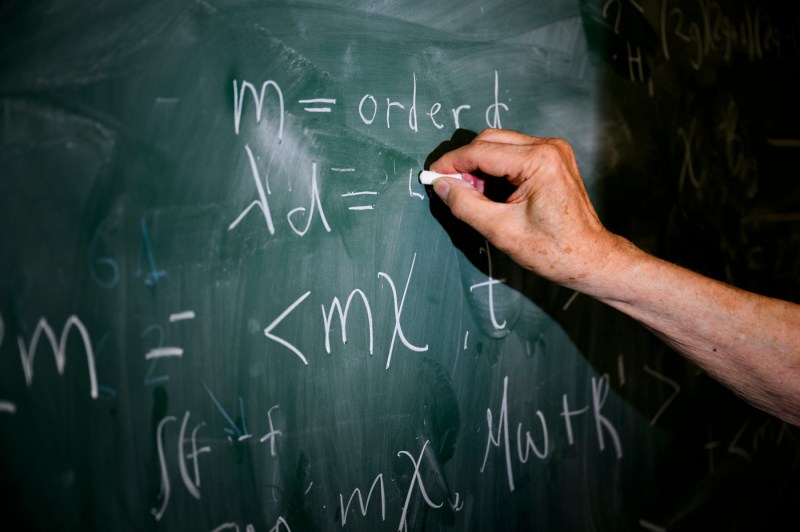 Solomon Jekel solving a math problem on a chalkboard.