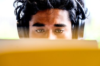 The top half of a person's face is wearing headphones. The person is focusing on their computer screen, obscuring the bottom half of the picture.