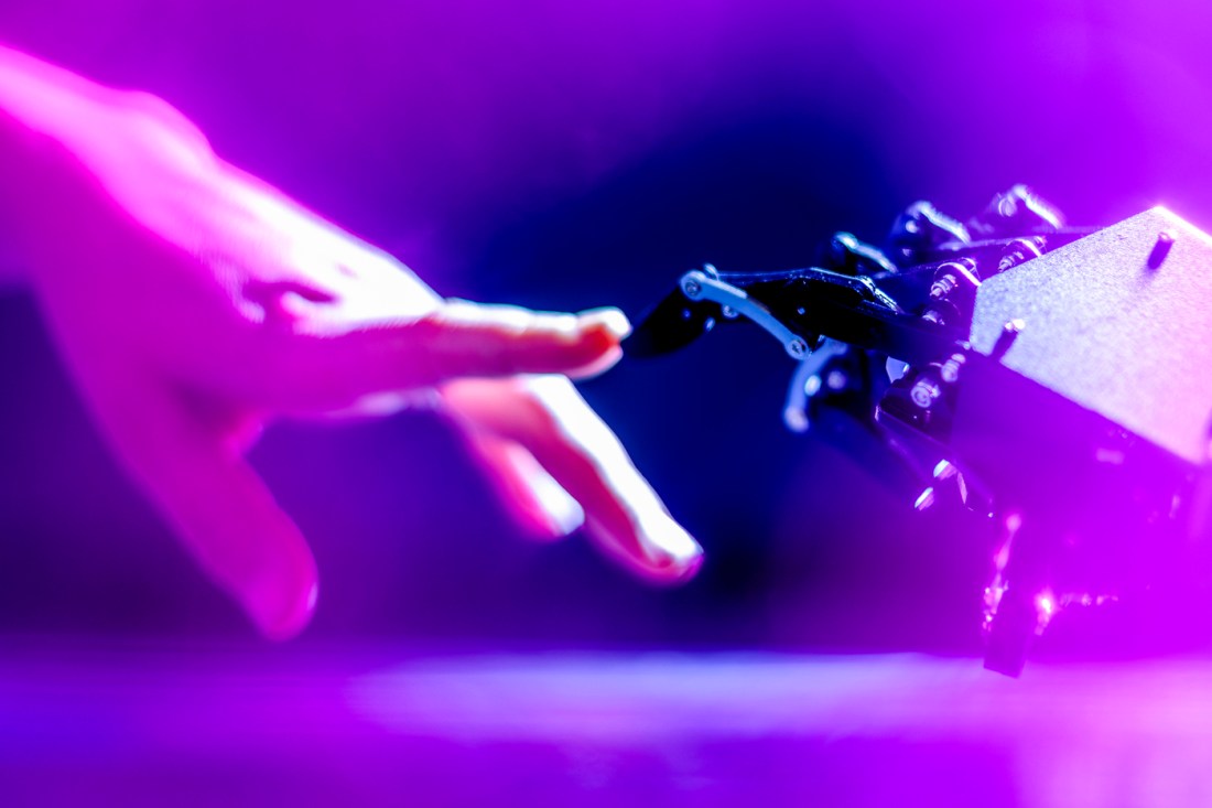 A person's hand reaching out to touch a robotic hand.