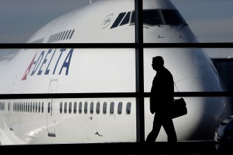 The silhouette of a person holding a briefcase walks in front of a grounded plane.