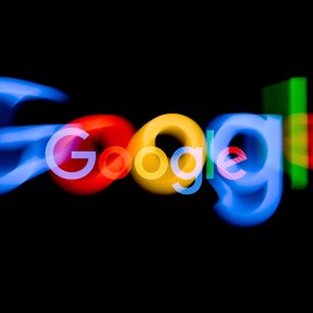 The colorful Google logo is blurred on top of a black background.