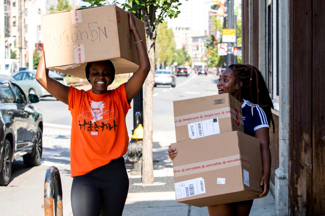 Students carrying boxes while moving in.