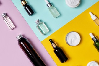 Creams, serums, and other skincare products are displayed laid on top of a bright background.