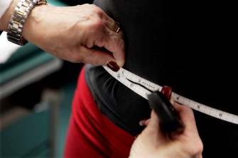 A person is measuring someone's waist with measuring tape.