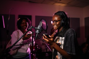 Northeastern students singing into a microphone in a studio.