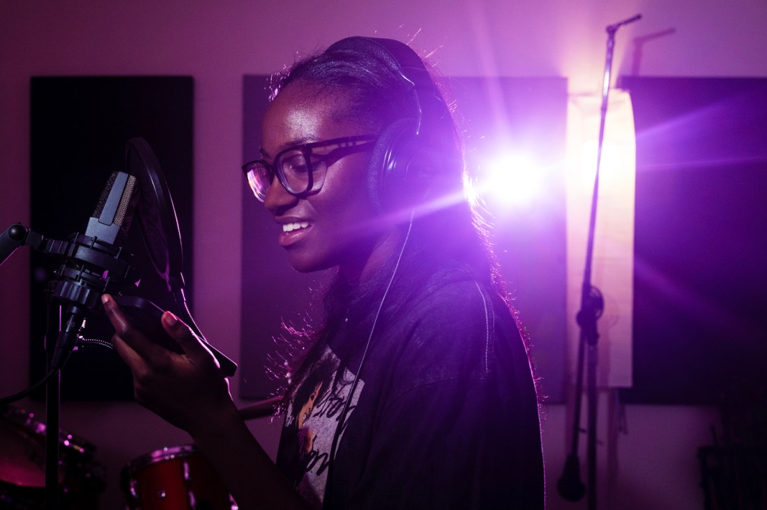 Brianna Charles recording on a mic in a studio.