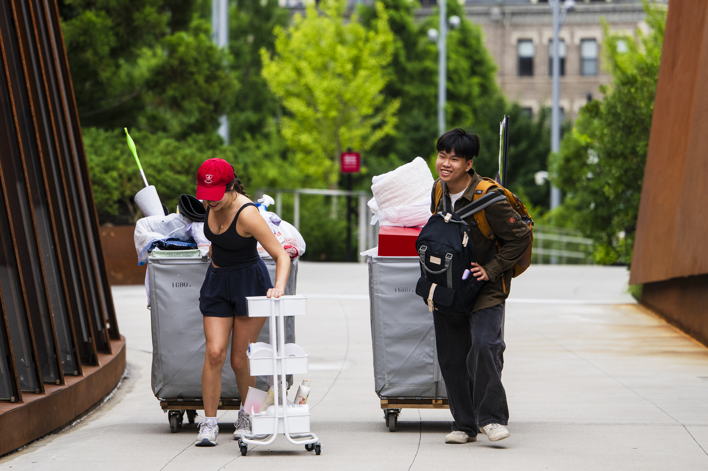 Students pull rolling bins full of their belongings over the bridge